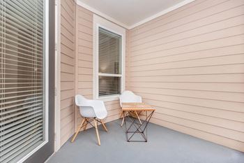 two chairs and a table on a porch with a window
